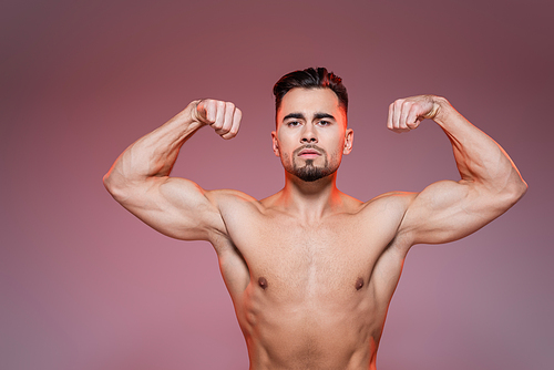 lighting on shirtless man showing muscles on pink and grey