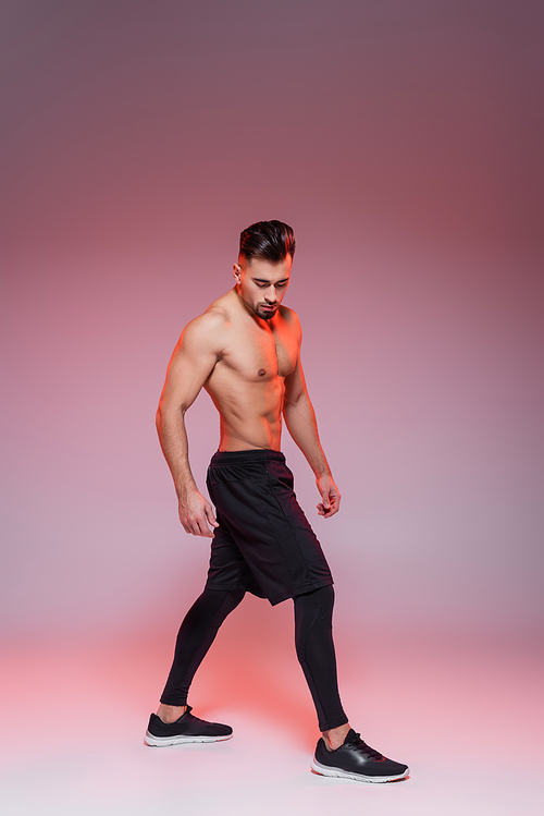 full length of shirtless sportsman posing on grey and pink