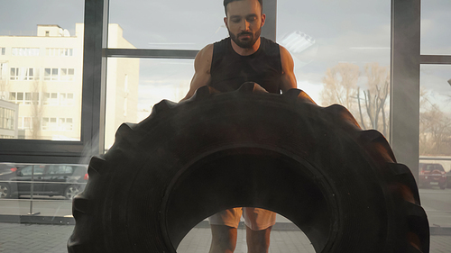 Sportsman lifting tire while training in gym