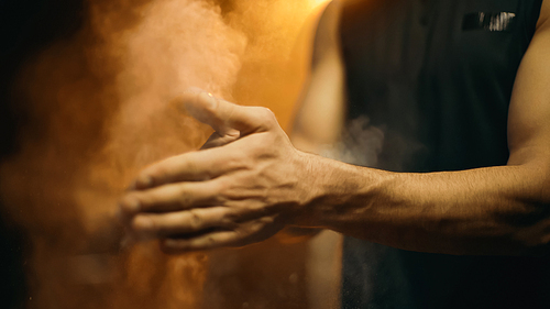 Cropped view of sportsman applying talc on hands on dark background