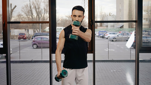 Sportsman holding dumbbells while training in gym