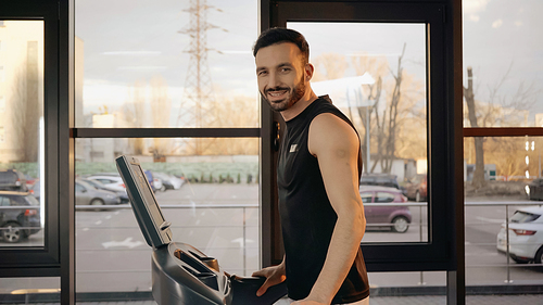 Smiling sportsman  while training on treadmill in gym