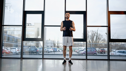 Brunette sportsman holding jump rope in gym