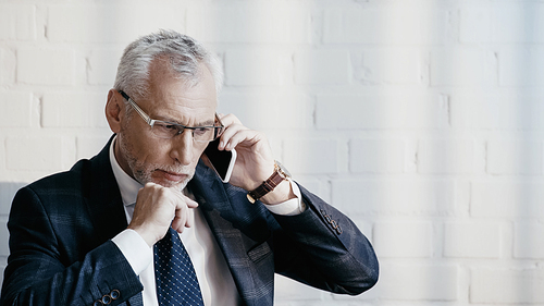 Pensive businessman talking on mobile phone in office