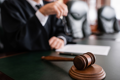 selective focus of wooden gavel near cropped judge on blurred background