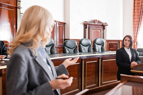 blurred attorney pointing with hand and talking to witness during litigation