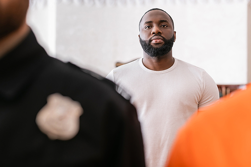 african american juryman standing near accused man and bailiff on blurred foreground