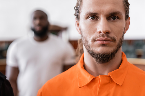bearded man in jail uniform  near blurred african american juryman