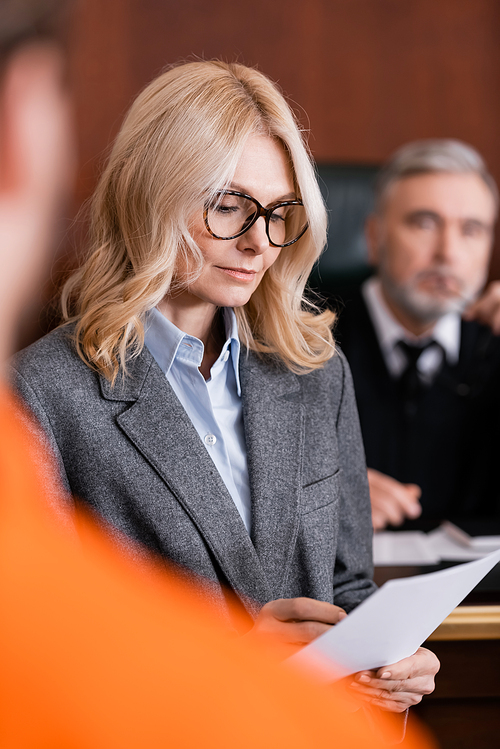 selective focus of attorney writing on paper near blurred judge and accused man on foreground