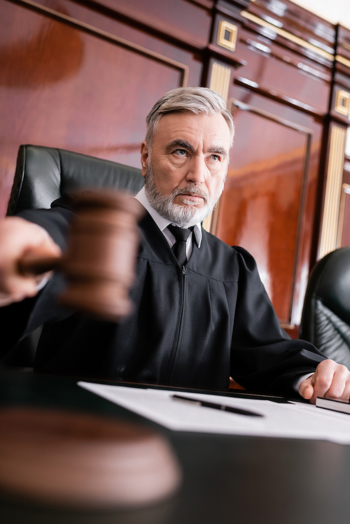 grey-haired judge with blurred gavel sentencing in courthouse