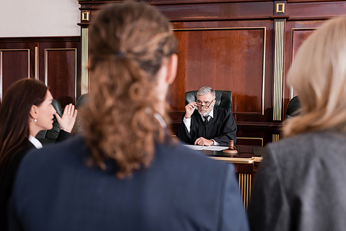 prosecutor pointing with hand while talking to judge near blurred man and advocate