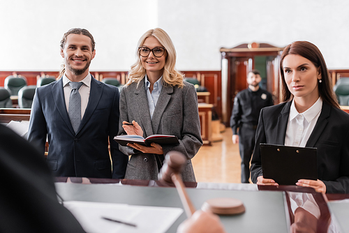 smiling advocate pointing with hand near happy businessman and judge on blurred foreground