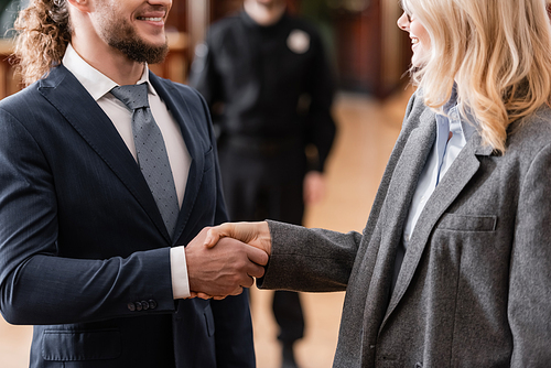 cropped view of smiling advocate shaking hands with happy businessman in court