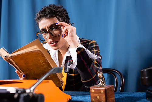 vintage style newswoman in eyeglasses reading book on blue background