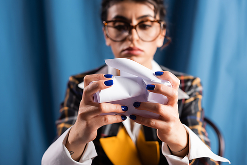 vintage style woman with blue manicure crumpling paper on blurred background