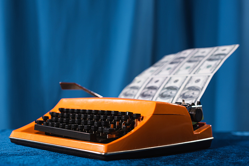 vintage typewriter and blurred dollar banknotes on blue background