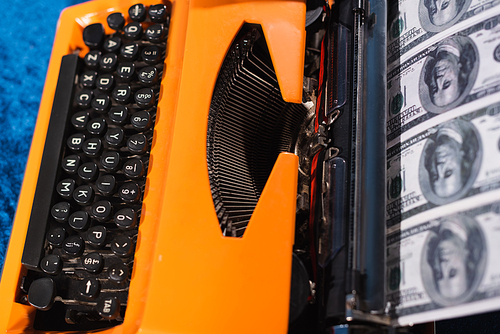 top view of retro typewriter and dollar banknotes, blurred foreground