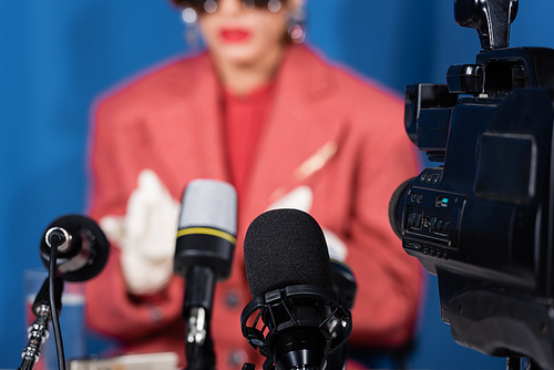 close up view of microphones and digital camera near cropped woman giving interview on blurred background