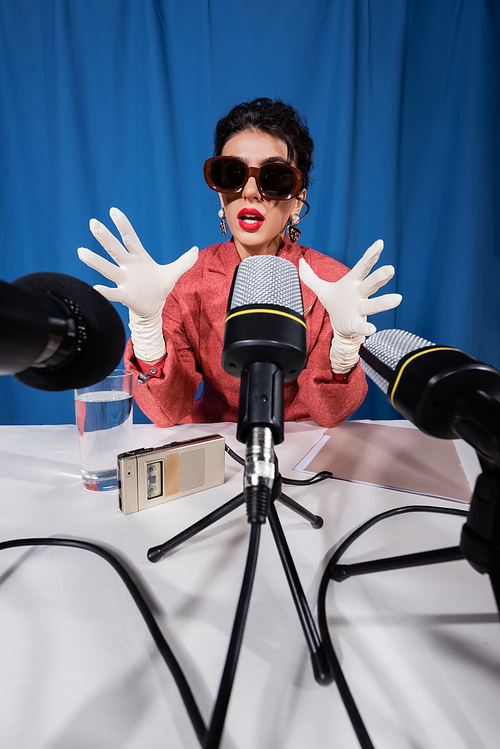 young vintage style woman gesturing during interview on blue background