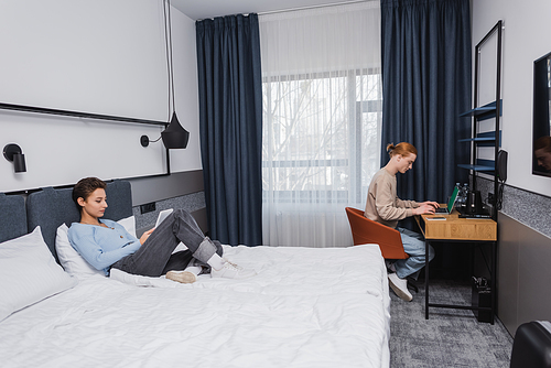 Young couple using devices in modern hotel room