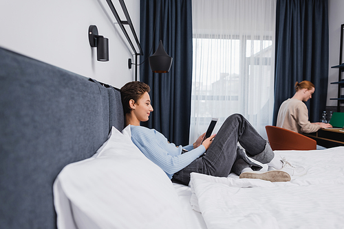 Side view of woman using digital tablet with blank screen near boyfriend in hotel room