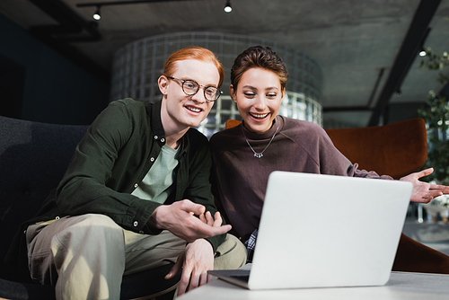 Positive couple having video call on laptop in hotel