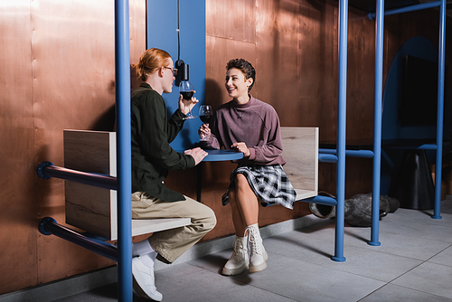 Happy young woman holding glass of wine near boyfriend in hotel