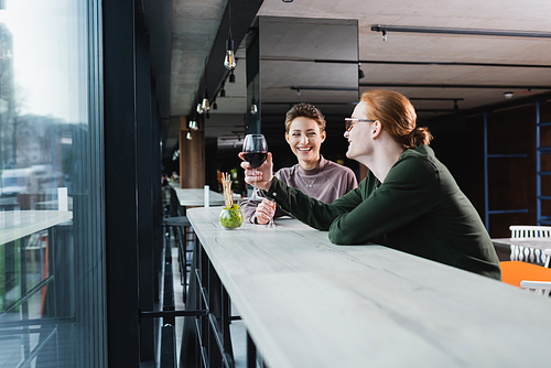 Smiling couple holding glasses of wine and talking in hotel