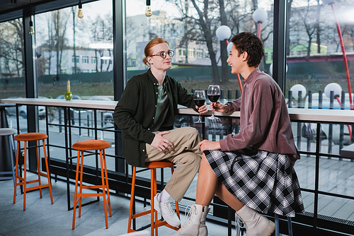 Positive couple of travelers holding glasses of wine in hotel