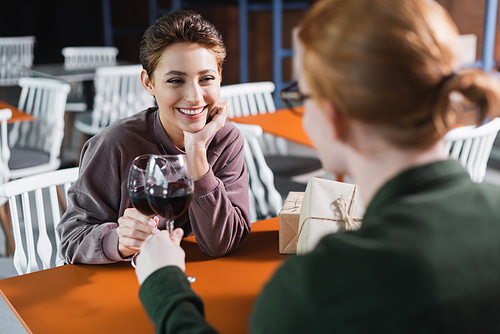 Young couple toasting with wine near presents in hotel cafe