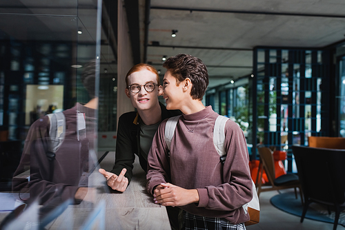 Cheerful travelers with backpack talking near hotel reception