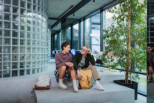 Young travelers with backpacks sitting on stairs in hotel