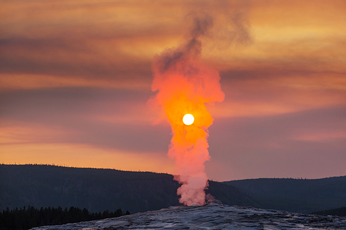Old Faithful Geyser Eruption in Yellowstone National Park at Sunset, Wyoming, USA