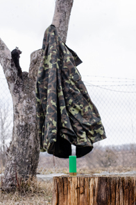 shotgun shell on wooden stump near camouflage jacket in woods