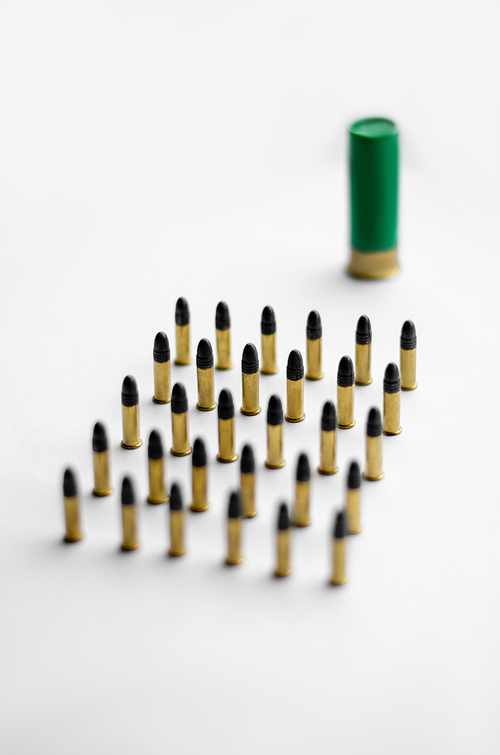 high angle view of bullets near blurred shotgun shell on white background