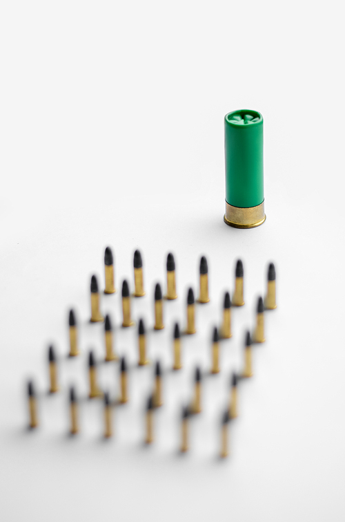 high angle view of blurred bullets near shotgun shell on white background