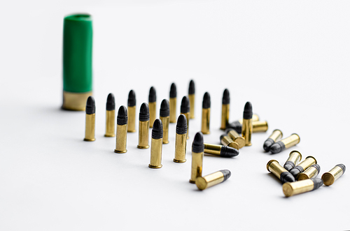 bullets near blurred shotgun cartridge on white background