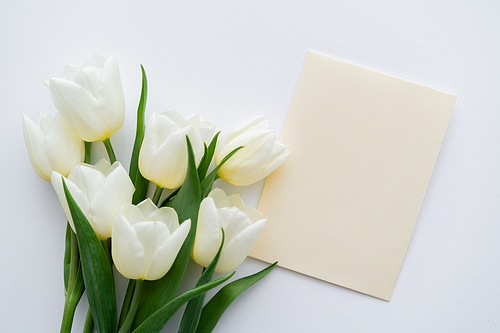 top view of bouquet with tulips near envelope on white background
