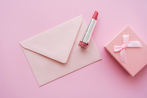 top view of lipstick near envelope and gift box on pink