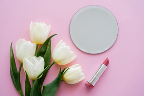 top view of white tulips near mirror and lipstick on pink