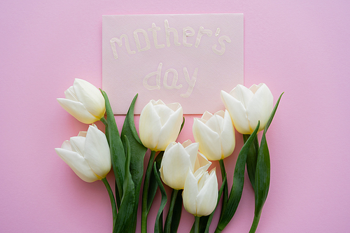 top view of envelope with mothers day lettering near white flowers on pink