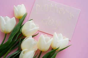 top view of envelope with mothers day lettering near blooming flowers on pink