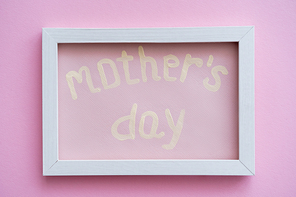 top view of greeting card with mothers day lettering in white frame on pink