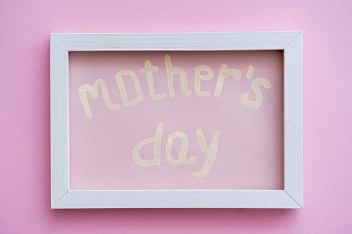 top view of greeting card with mothers day lettering in white frame on pink