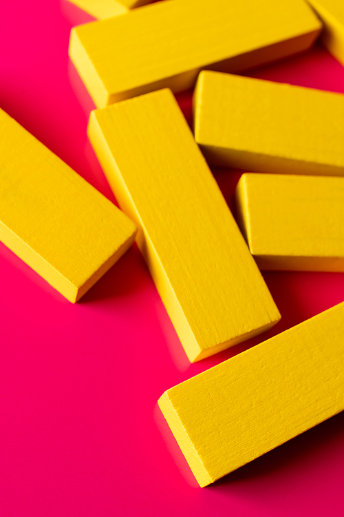 close up of yellow quadrangular blocks on pink background, top view