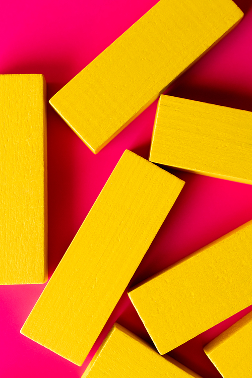 close up of bright yellow blocks on pink background, top view