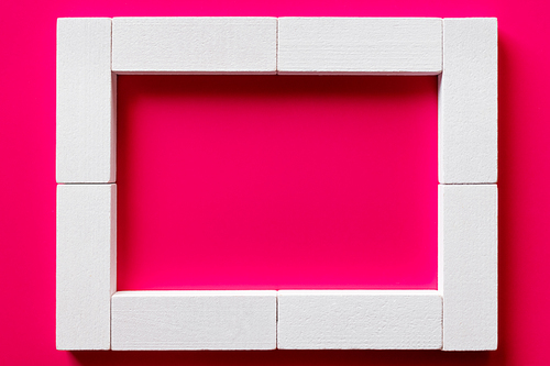 top view of white blocks frame on pink background