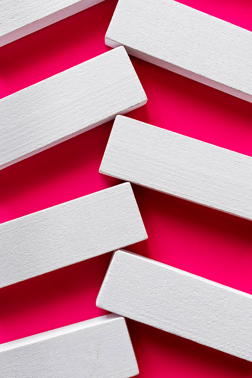 close up of white blocks on bright pink background, top view