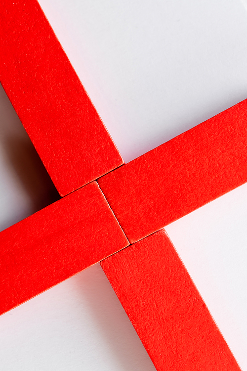 close up of cross made of red blocks on white background, top view