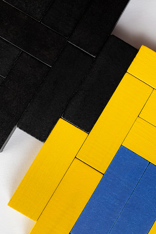 close up of blue, black and yellow blocks on white background, top view